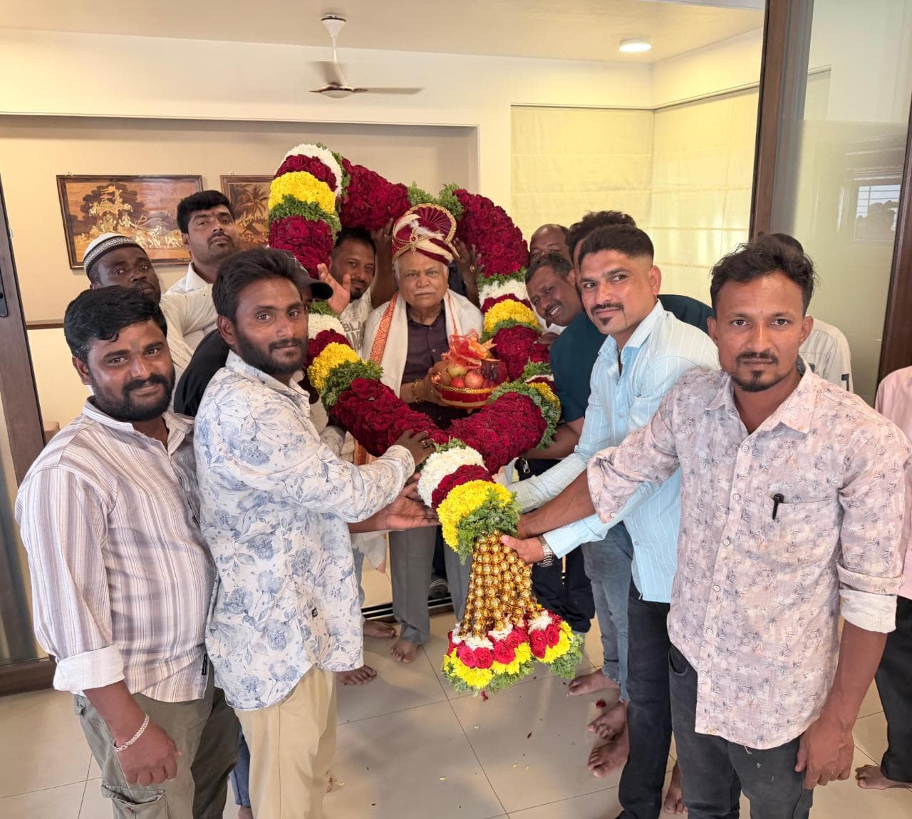 Babu Siddi and supporters greeting R. V. Deshpande with a flower garland at his residence in Haliyal